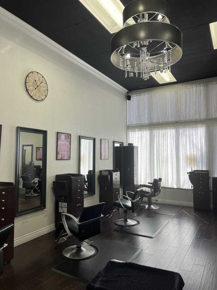 Elegant hair salon interior with stylish chairs, mirrors, chandelier, and modern decor.
