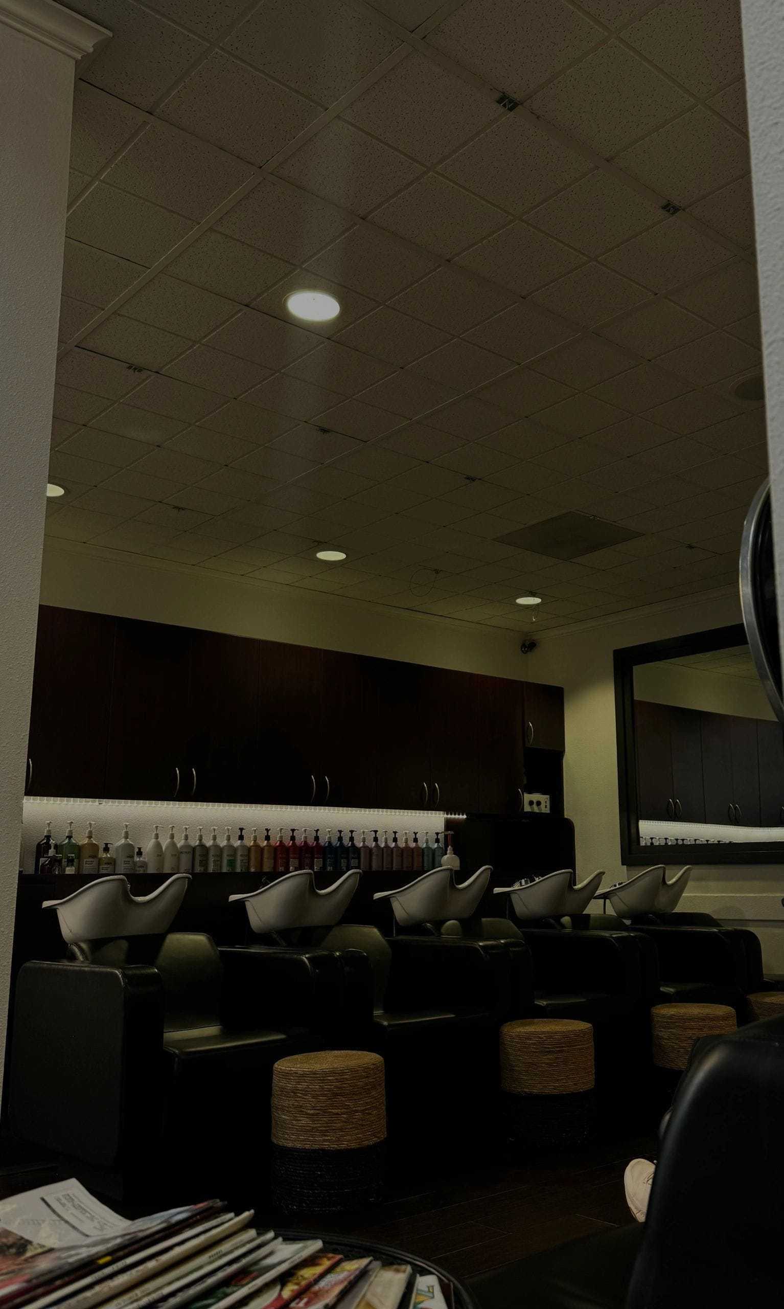 Modern hair salon with shampoo stations and products on shelves.