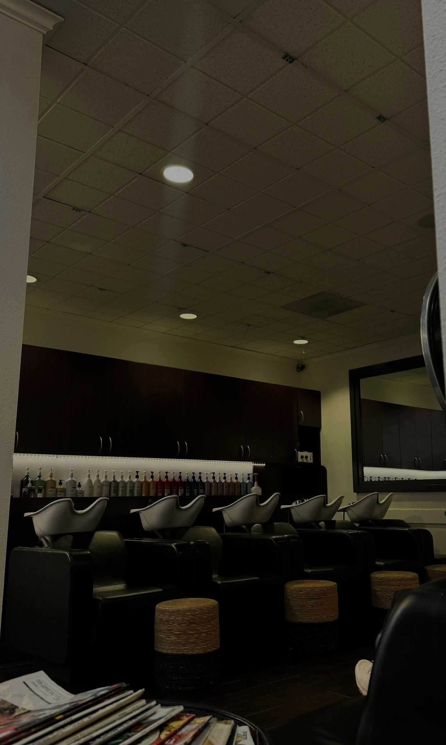 Modern hair salon with shampoo stations and products on shelves.